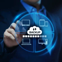 A person interacts with a digital screen displaying icons of various devices around a central cloud labeled "backup," symbolizing data backup across multiple devices.